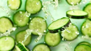 Pieces of fresh cucumber with splashes of water fly up and rotate in flight. On a green background. Filmed on a high-speed camera at 1000 fps. video