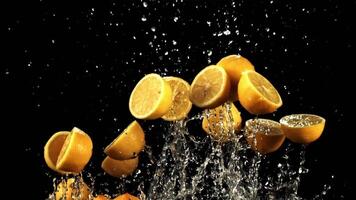 Pieces of lemon with drops of water fly up and fall. On a black background. Filmed on a high-speed camera at 1000 fps. video