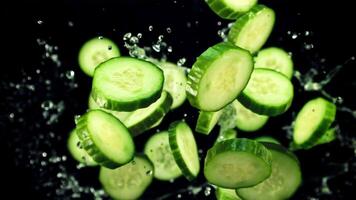 Pieces of fresh cucumbers fly up with drops of water. On a black background.Filmed on a high-speed camera at 1000 fps. video