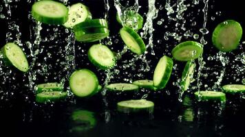 Pieces of fresh cucumbers with drops of water fly up and fall. On a black background.Filmed is slow motion 1000 fps. video