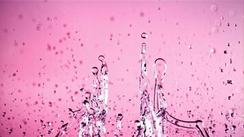 Water droplets rise up and fall. On a pink background. Filmed on a high-speed camera at 1000 fps. video