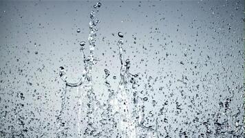 Splashes of water rise up and rotate in flight. On a blue background.Filmed on a high-speed camera at 1000 fps. video