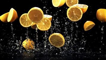 Pieces of lemon with drops of water fly up and fall on the table. On a black background. Filmed on a high-speed camera at 1000 fps. video