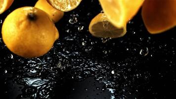 Halves of juicy lemon fall with splashes of water. On a black background. Filmed is slow motion 1000 fps. video