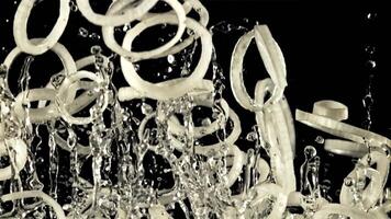 A pile of sliced onion rings with drops of water soars up and falls down. On a black background. Filmed on a high-speed camera at 1000 fps. video