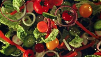 Pieces of cucumbers, tomatoes, lettuce and onions fly up and rotate in flight. Top view. On a black background. Filmed on a high-speed camera at 1000 fps. video