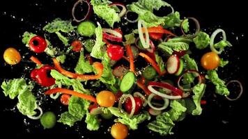 Pieces of cucumbers, tomatoes, lettuce and onions fly up and rotate in flight. Top view. On a black background. Filmed on a high-speed camera at 1000 fps. video