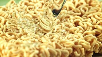 Water with splashes pours on the dry noodles. Macro background. Filmed is slow motion 1000 fps. video