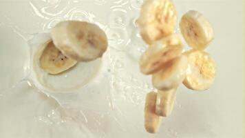 Pieces of banana fall into the milk with splashes. On a white background. Filmed is slow motion 1000 fps. video