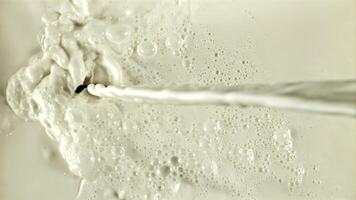 A stream of milk flows with splashes and air bubbles. On a white background. Filmed on a high-speed camera at 1000 fps. video