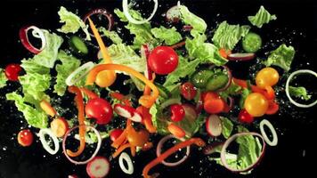 Chopped vegetables with drops of water fly up and fall down. Top view. On a black background. Filmed on a high-speed camera at 1000 fps. video