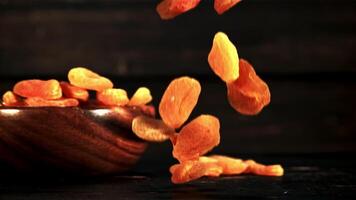 Dried apricots fall to the table. On a wooden background. Filmed is slow motion 1000 fps. video