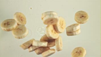 Pieces of fresh bananas fall into the milk with splashes. Macro background. Filmed on a high-speed camera at 1000 fps. video