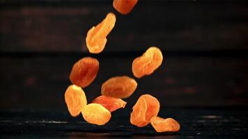 Dried apricots fall to the table. On a wooden background. Filmed is slow motion 1000 fps. video