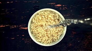 Water pours into the bowl with noodles. Top view. Against a dark background. Filmed on a high-speed camera at 1000 fps. video