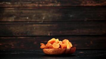 Dried apricots fall with a wooden plate and rotate in flight. On a wooden background. Filmed is slow motion 1000 fps. video