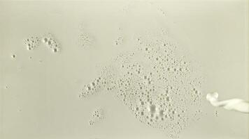 A stream of milk flows with air bubbles. Top view. On a white background. The texture of milk. Filmed on a high-speed camera at 1000 fps. video