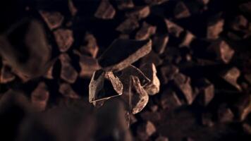 Pieces of chocolate fall down. Top view. Against a dark background. Filmed on a high-speed camera at 1000 fps. video