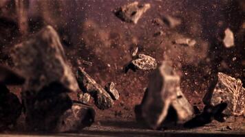 Pieces of chocolate fall and rotate in flight. Against a dark background. Filmed is slow motion 1000 fps. video