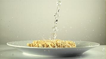 A jet of water with splashes falls on the dry noodles. On a white background. Filmed on a high-speed camera at 1000 fps. video