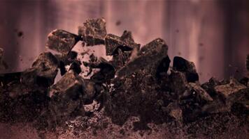 Pieces of chocolate fly up and fall down. Against a dark background. Filmed is slow motion 1000 fps. video