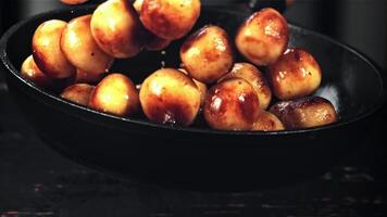 Fried potatoes are tossed in a frying pan with a splash of oil. On a black background. Filmed is slow motion 1000 fps. video