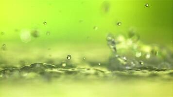 gotas de agua chapoteo en el superficie. en un verde antecedentes. filmado es lento movimiento 1000 fps. video