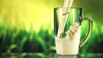 A stream of milk pours into a mug of spray. Against the backdrop of green grass. Filmed on a high-speed camera at 1000 fps. video