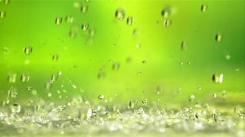 agua gotas otoño con salpicaduras en un verde fondo.filmado es lento movimiento 1000 fps. video