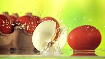 A boiled egg falls on the table and breaks up into halves. On a green background. Filmed is slow motion 1000 fps. video