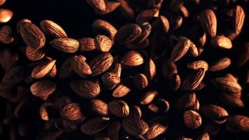 Almonds rise up and fall down. Top view. On a black background. Filmed on a high-speed camera at 1000 fps. video