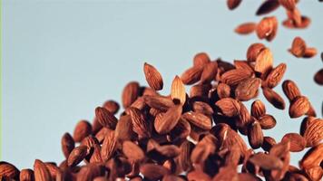 Almonds go up and fall. On a blue background. Filmed is slow motion 1000 fps. video