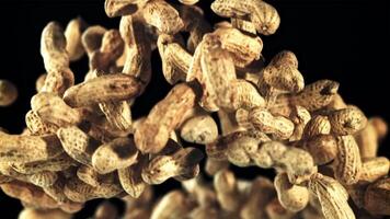 A pile of peanuts in the shell rises up and falls down. On a black background. Filmed is slow motion 1000 fps. video