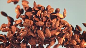 Almonds go up and fall. On a blue background. Filmed is slow motion 1000 fps. video