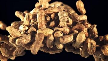 A pile of peanuts in the shell rises up and falls down. On a black background. Filmed is slow motion 1000 fps. video