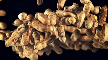 A pile of peanuts in the shell rises up and falls down. On a black background. Filmed is slow motion 1000 fps. video