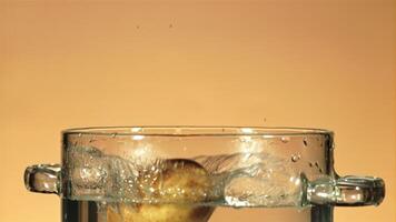 Fresco patatas otoño dentro un maceta de agua con salpicaduras en un naranja antecedentes. filmado en un alta velocidad cámara a 1000 fps. video