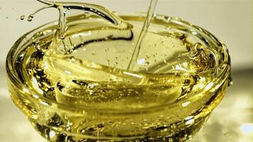 A stream of olive oil falls into a glass bowl. Macro background. Filmed on a high-speed camera at 1000 fps. video