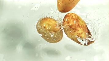 Potatoes fall into the water with splashes. Macro background. Filmed on a high-speed camera at 1000 fps. High quality FullHD footage video