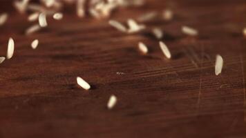 Raw rice is scattered on the table and rotated. On a wooden background.Filmed on a high-speed camera at 1000 fps. video