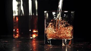 Cognac ist gegossen in das Glas mit ein Whirlpool. auf ein schwarz Hintergrund. gefilmt auf ein schnelle Geschwindigkeit Kamera beim 1000 fps. hoch Qualität fullhd Aufnahmen video