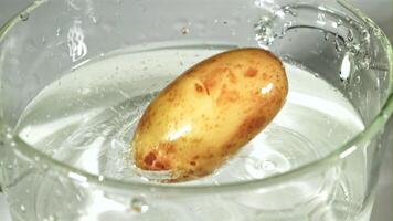 Potatoes fall into a clear pot with splashes of water. Macro background. Filmed on a high-speed camera at 1000 fps. video