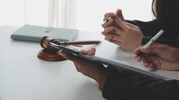 Justice and Law concept. Legal counsel presents to the client a signed contract with gavel and legal law or legal having team meeting at law firm in background video