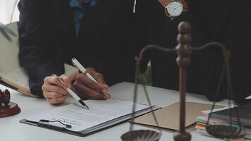 Justice and Law concept. Legal counsel presents to the client a signed contract with gavel and legal law or legal having team meeting at law firm in background video