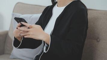 sonriente mujer de negocios utilizando teléfono en oficina. pequeño negocio empresario mirando a su móvil teléfono y sonriente. video