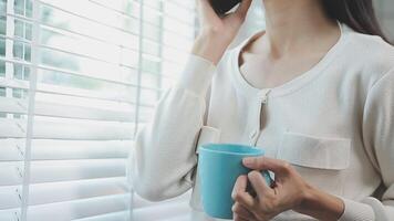 encantador mujer con hermosa sonrisa leyendo bueno Noticias en móvil teléfono durante descanso en café comercio, contento caucásico hembra acecho su fotos en célula teléfono mientras relajante en café durante gratis hora video