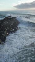 verticaal video van zee golven crashen in de pier antenne visie