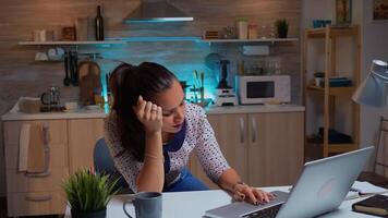 Woman closing eyes because of exhaustion while working on a project for work late at night. Busy exhausted remote employee napping on chair waking up reading on laptop using modern technology network photo