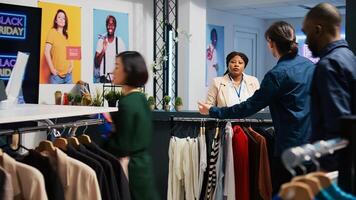 Happy customer at checkout counter in retail store, buying new clothes during black friday event. Young man carrying stander full of clothing items and accessories, seasonal sales obsession. photo