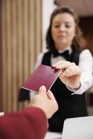 Hotel concierge checks passport, taking identification files from guest to fill in papers and help him settle in. Businessman in suit travelling for corporate work trip. Close up. photo
